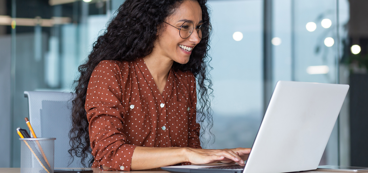 Une femme hispanique travaillant sur un ordinateur portable dans un bureau moderne.