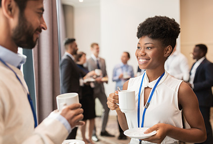 Two people with cups of coffee chatting at a conference.