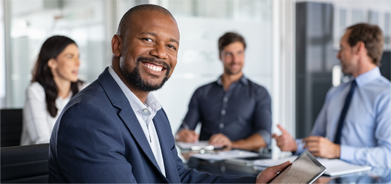 Smiling businessman holding a tablet during a meeting.